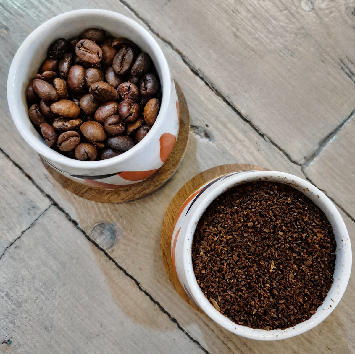 Colombian themed cups filled with whole beans and ground coffee on a wooden background